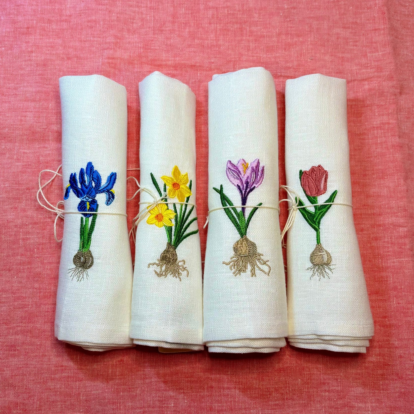 Linneservetter med fyra olika vårblommor vårlökar broderade. Blå iris, gul påsklilja, rosa tulpan och lila krokus. Alla blommor har sina lökar med. Ett set tygservetter med vårtema
