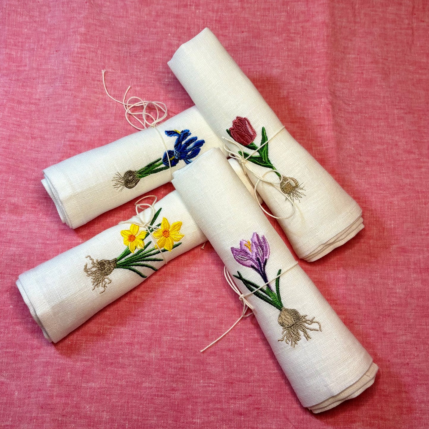 Linneservetter med fyra olika vårblommor vårlökar broderade. Blå iris, gul påsklilja, rosa tulpan och lila krokus. Alla blommor har sina lökar med. Ett set tygservetter med vårtema
