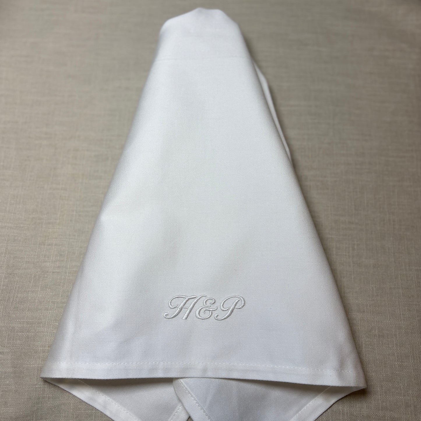 Klassiska lyxiga vita tygservetter av tät och fin bomull. Lika lyxiga som linneservetter. Monogram broderas. Vitt monogram i kursiv stil på den vita tygservettens nedre del: H&P