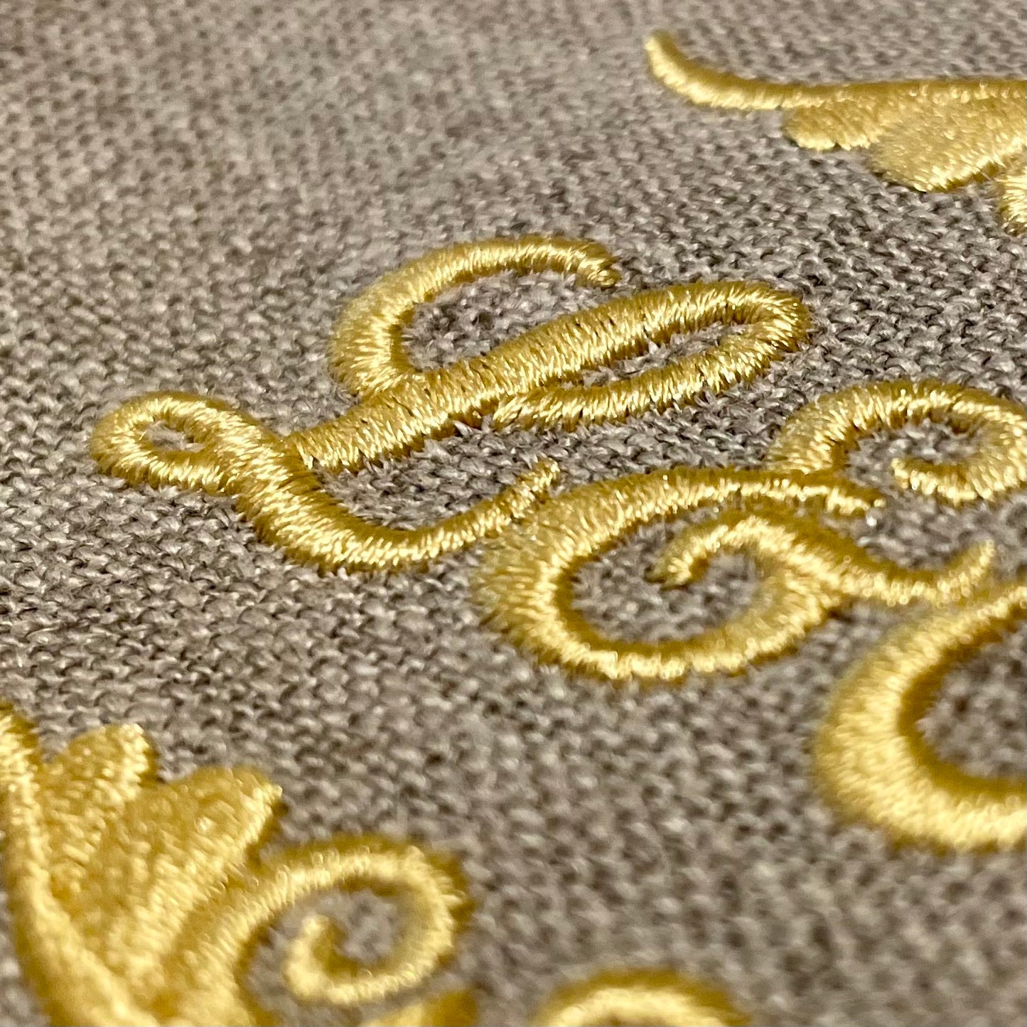 Närbild broderat monogram initialer på hellinne kökshandduk oblekt linne. Broderi på beställning. Unikt och personligt. Gyllene Tråden.