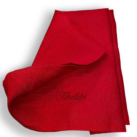 Linnehandduk med broderat namn. Handduken är röd, av 100% linne och det är broderat Hedås med mörkare röd tråd.