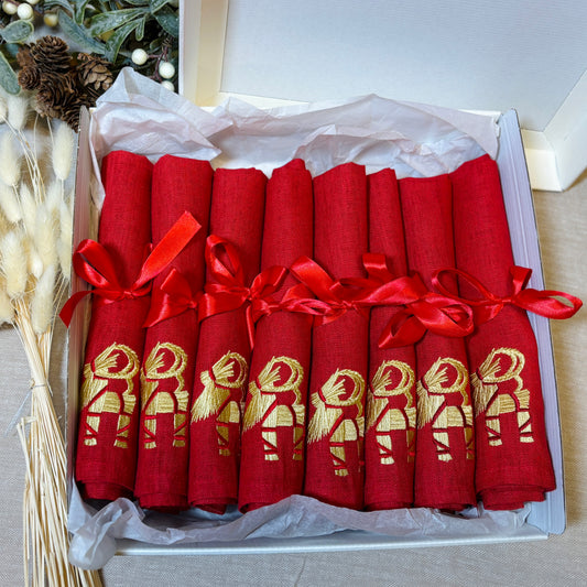 Röda linneservetter med broderade halmbockar i guldfärgad och röd tråd. Röd rosett kring varje servett. 8-pack i en krämvit presentkartong.