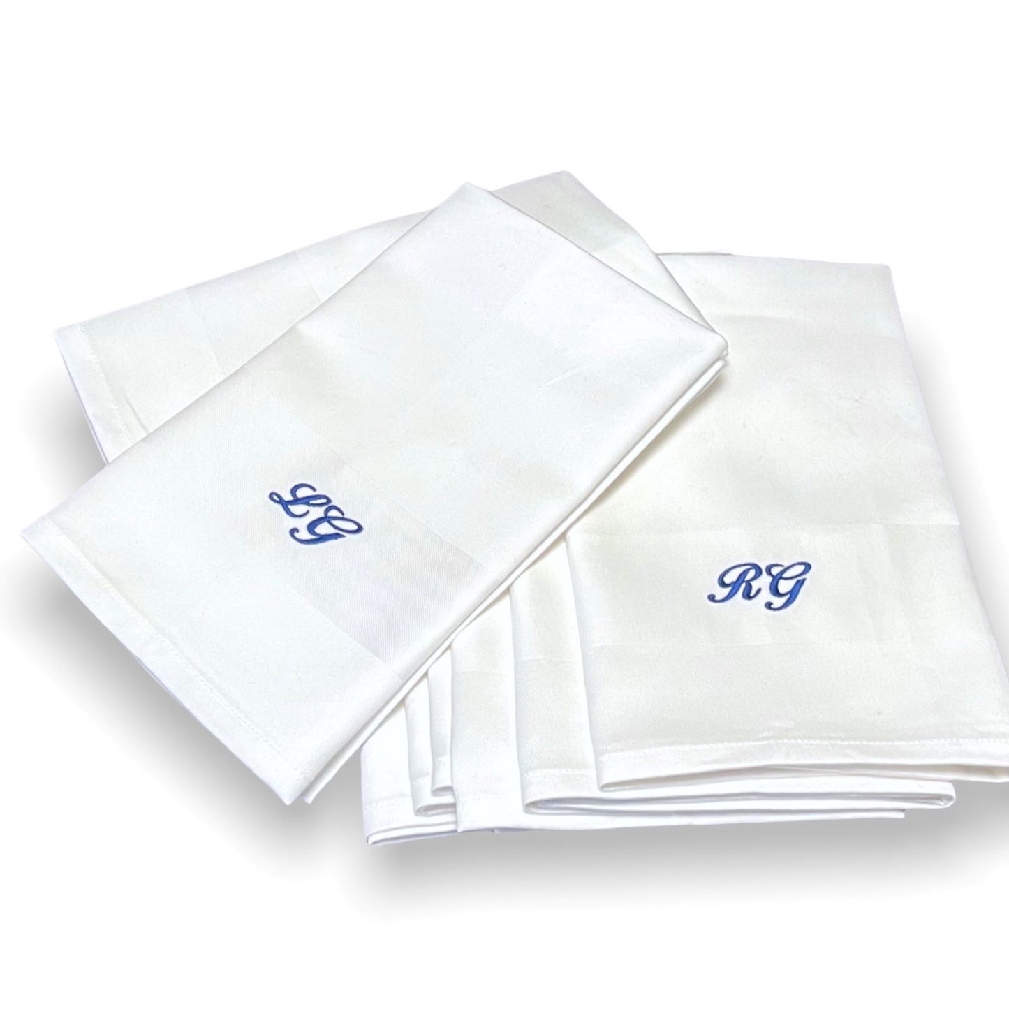 Klassiska lyxiga vita tygservetter av tät och fin bomull. Monogram broderas på servetten. Blått monogram på vit tygservett är klassiskt och tidlöst.